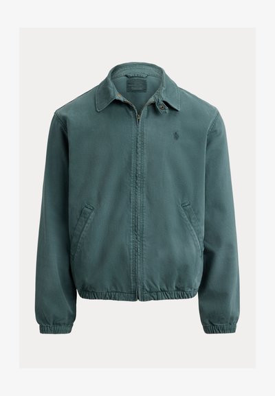 Žalia medvilninė striukė su smailiu apykakliu, priekyje su užtrauktuku ir šoninėmis kišenėmis. Yra elastinės rankogaliai ir mažas logotipas ant krūtinės.