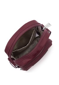Piccola borsa crossbody color maroon con scomparto principale aperto che mostra due tasche interne e una zip argentata su sfondo bianco.