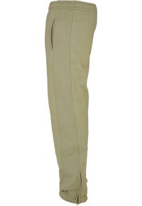 Light olive green sweatpants made of soft fabric, featuring an elastic waistband, side pockets, and zippered cuffs at the ankles.