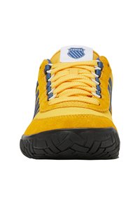 Sneakers jaunes et bleu marine avec une semelle texturée noire, des lacets jaunes et une étiquette blanche sur la langue portant le logo K-Swiss, vue de face.