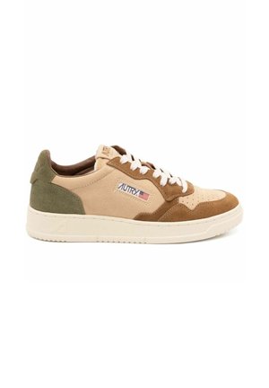 Beige og brun ruskinds sneaker med hvide snørebånd, der har en polstret pløs, teksturerede detaljer og et logo-patch på siden.
