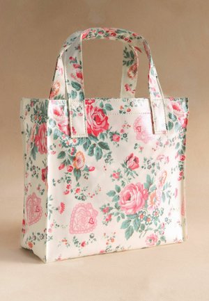 Pieni suorakaiteen muotoinen kangaskassi, jossa on kaksi kantokahvaa. Se on koristeltu vaalealla pohjalla vaaleanpunaisilla ja punaisilla ruusuilla, vihreillä lehdillä ja vaaleanpunaisilla sydänkuvioilla.