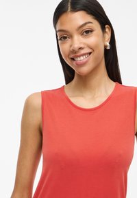 Top rojo sin mangas de tela suave, con un escote redondo y una textura lisa, diseño ajustado que enfatiza la parte superior del cuerpo.