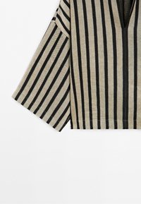 Beige fabric with black vertical stripes, showing a wide sleeve and V-neck detail on a garment.