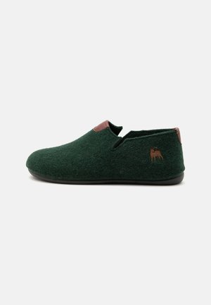 Mørkegrøn filt slip-on sko med brun læderkant og lille brun broderet hundelogo på ydersiden.