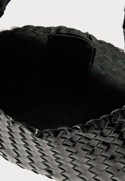 Saco tejido preto com formato redondo, apresentando material brilhante e superfície texturada. O interior é preto com um acabamento suave.