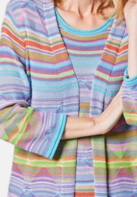 Multikleurige gebreide cardigan met gestreepte patronen in paars, roze, groen, blauw en oranje. Lichtgewicht, met lange mouwen en een open voorkant.