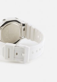 Weißer Silikonarmbanduhr mit einem runden Gehäuse aus Schwarz und Silber, ausgestattet mit einer Edelstahlspange und perforierten Armbandlöchern zur Anpassung.