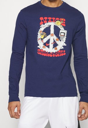 Granatowa koszula z długim rękawem z kolorowym znakiem pokoju z chmur, piłek do koszykówki, obręczy, ptaka, słońca oraz czerwonym tekstem "Nike Basketball" na przodzie.