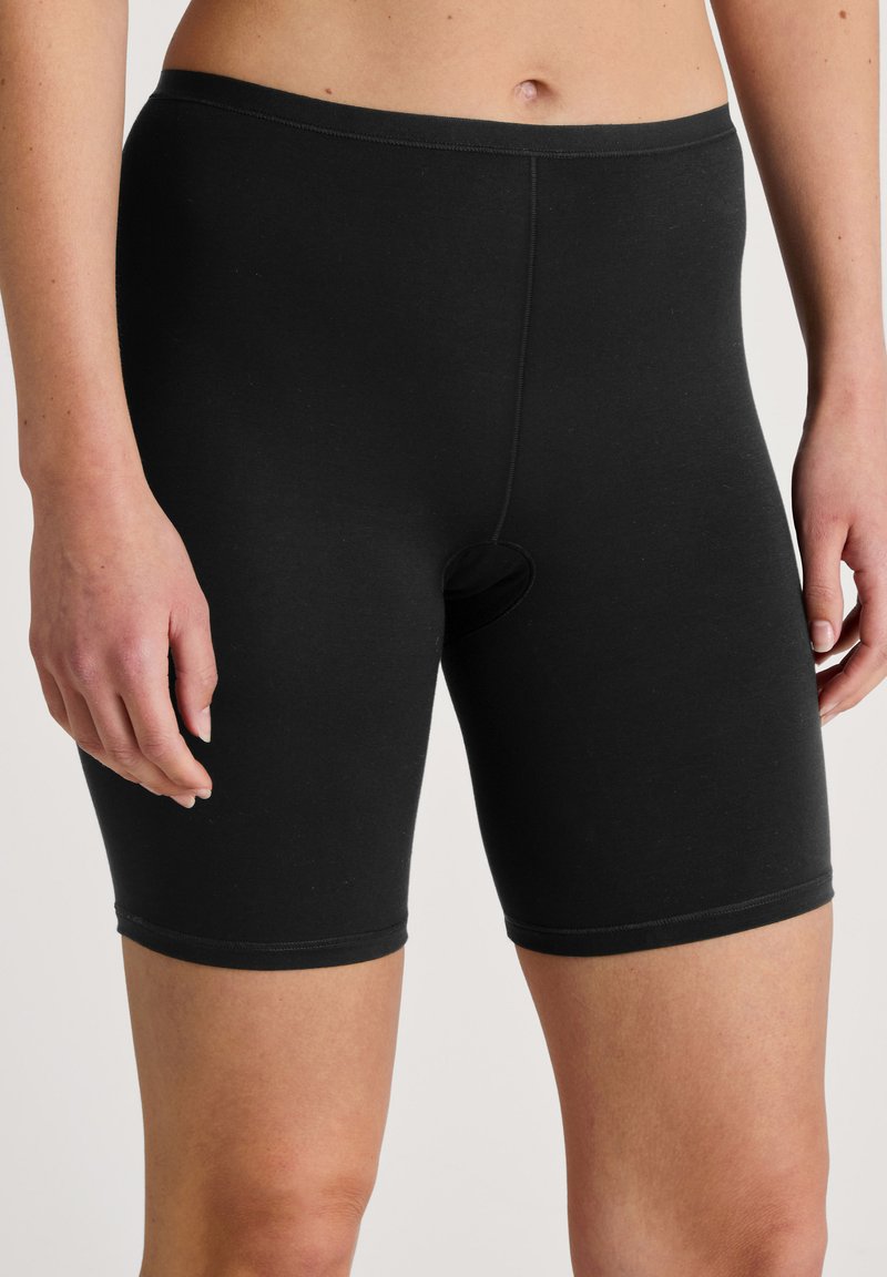 Zwarte stretchshorts van zacht materiaal, met een elastische tailleband en een ronde uitsnede aan de voorkant. Korte lengte, getailleerd ontwerp.