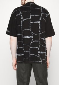 Černé tričko s krátkým rukávem, které má opakující se vzor textu "Armani Exchange" v šedé barvě. Vyrobeno z lehké tkaniny s volným střihem.