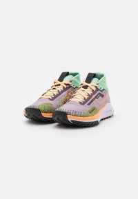 Scarpe da corsa viola e verdi con tomaia in rete, lacci arancioni e suole testurizzate, dotate di un logo e accenti a contrasto.