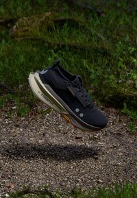 Men's running shoe featuring a black mesh upper, beige midsole, and orange outsole. Includes a lacing system and reflective detailing.