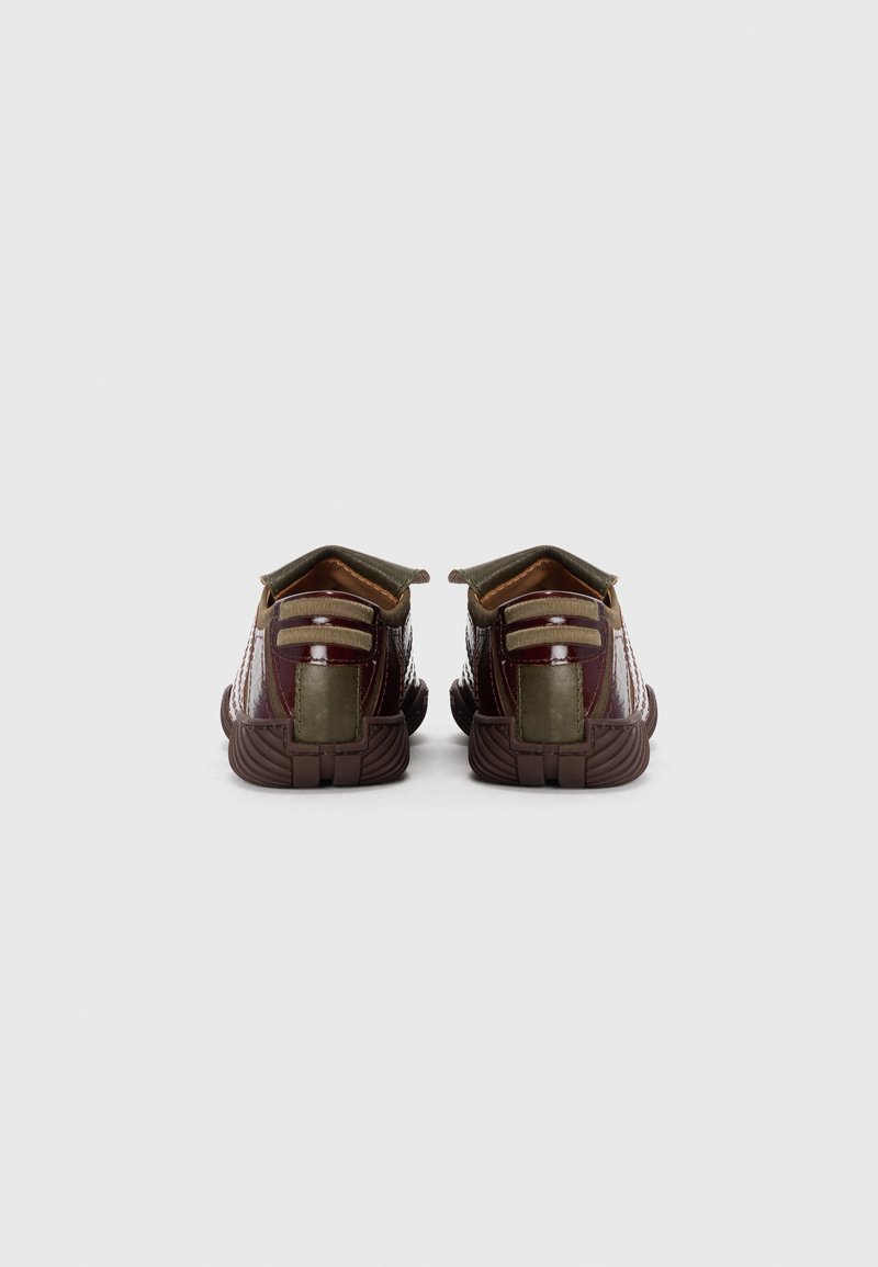 Brown and gold athletic shoes with textured fabric, a reinforced heel, and striped detailing. Features pull tabs for easy wear.