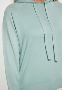 Felpa con cappuccio di un azzurro chiaro caratterizzata da una texture a coste, con coulisse regolabile e maniche raglan. Tessuto morbido e vestibilità comoda.