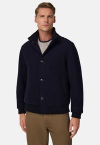 Námořnická bunda z vlněné směsi s vysokým límcem, předními knoflíky, bočními kapsami a žebrovanými manžetami a spodním lemem; navržena pro pohodlný střih.