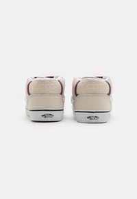 Tenisky Vans v béžovo-maroónovej farebnej kombinácii, hladká a štruktúrovaná koža, polstrovaný golier a biela podrážka s logom na päte.