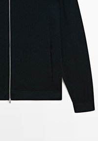 Felpa nera con zip realizzata in tessuto morbido. Presenta una cerniera metallica, maniche lunghe e polsini e orlo a coste. Inclusi tasche laterali.