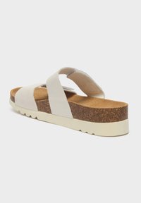 Sandalo platform in pelle bianca con due strisce larghe, una soletta in sughero testurizzato e una suola in gomma bianca. Design minimalista, senza decorazioni.