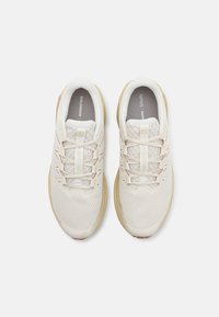 Leichte Laufschuhe mit einem atmungsaktiven Mesh-Obermaterial in hellem Creme, ausgestattet mit reflektierenden Akzenten und einer strukturierten Außensohle für Traktion.
