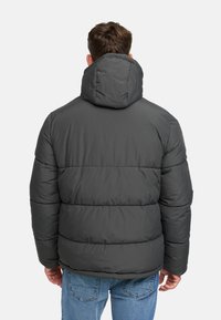 Szara kurtka puchowa z odpinanym kapturem, poziomymi szwami i gładką fakturą. Nosi ją osoba w niebieskich dżinsach, widoczna z tyłu.