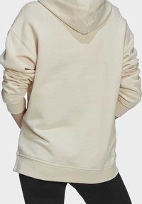 Béžová mikina s volným střihem, kapucí, vroubkovanými manžetami a lemem. Měkká látka s hladkou texturou, bez viditelných vzorů nebo akcentů.