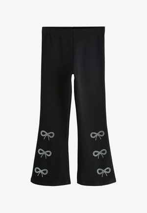 Leggings neri realizzati in materiale elasticizzato, con decorazioni a fiocco di rhinestone sulla parte inferiore della gamba, silhouette aderente e polsini svasati.