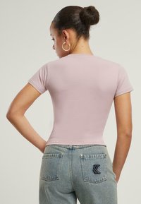 Rosa tettskjorte med korte ermer, sammen med lysebl�å høytlivsjeans med teksturert stingdetalj på baklommene.