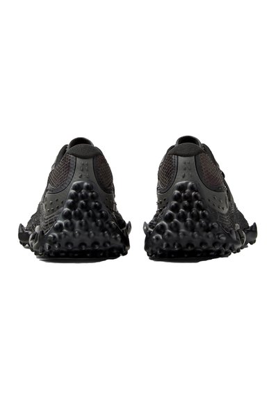 Par af sorte sportssko set bagfra, med teksturerede såler med afrundede fremspring og overdeler af meshstof.