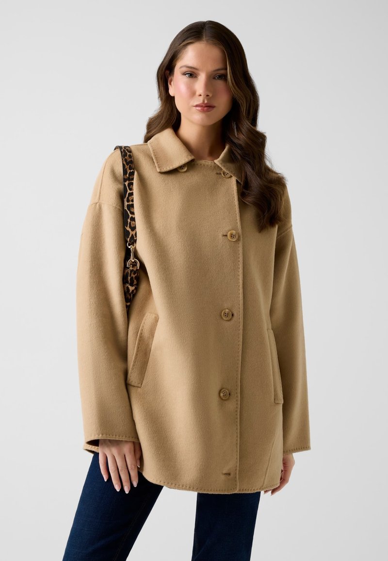 Cappotto in misto lana beige con colletto, bottoni frontali e tasche laterali. Arricchito da una fascia con stampa leopardata.