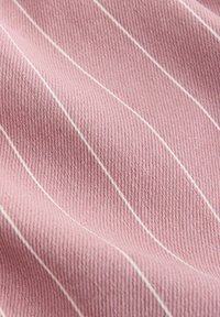 Soft pink fabric with fine white vertical stripes, showing a textured weave and gentle folds.
