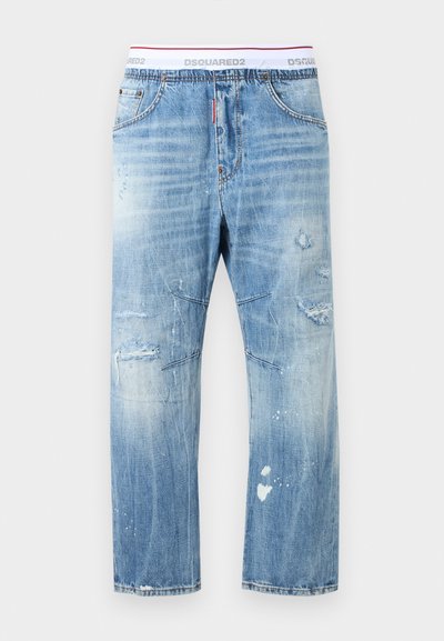 Ανοιχτό μπλε τζιν με φθορές, ξεθωριασμένα σημεία, σκισίματα και φθαρμένες λεπτομέρειες, σε συνδυασμό με λευκό ελαστικό ζωνάκι με τη λέξη "DSQUARED2".