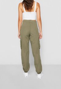 Pantalons cargo vert olive avec des jambes fuselées, des poignets élastiques et de grandes poches latérales. Fabriqués en tissu léger, conçus pour le confort et la mobilité.