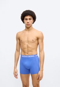 Μπλε μπόξερ με λευκή ελαστική μέση με την επιγραφή "BJÖRN BORG". Με λεία υφή και εφαρμοστή σχεδίαση, περιλαμβάνει ένα σχήμα θήκης για υποστήριξη.