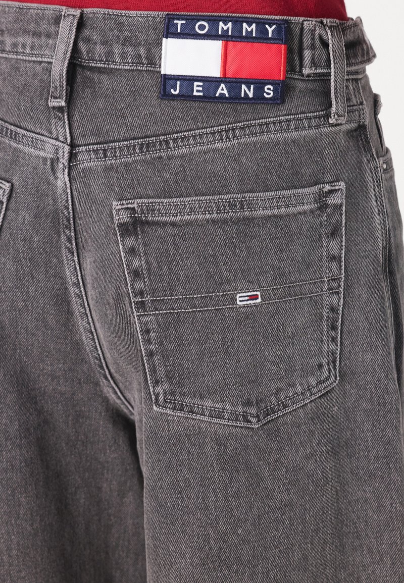 Graue Jeans aus Denim mit einer markanten Textur, ausgestattet mit einem Tommy Jeans-Logo-Patch am Bund und einem kleinen Logo auf der Gesäßtasche.