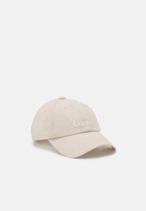 Beige Baseballkappe mit gebogenem Schirm, vorne auf dem Panel mit dem Wort "Études" bestickt, fotografiert vor weißem Hintergrund.