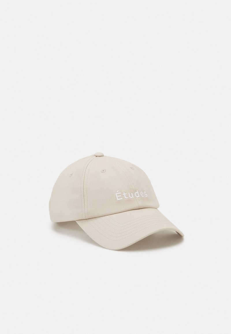 Casquette de baseball beige à visière courbée, brodée du mot « Études » sur le panneau avant, photographiée sur un fond blanc.