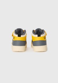 Mid-top sneakers in yellow, gray, and cream. Features a textured finish, padded collar, and a heel tab for easy wear. Patterned outsoles.