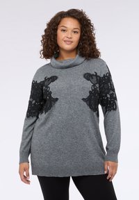 Pulover gri cu guler în formă de cowl și mâneci lungi, având detalii din dantelă neagră pe față. Textură moale, cu un croi lejer.