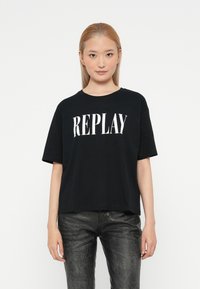 Černé bavlněné tričko s velkým bílým potiskem "REPLAY". Krátké rukávy, kulatý výstřih a volný střih.