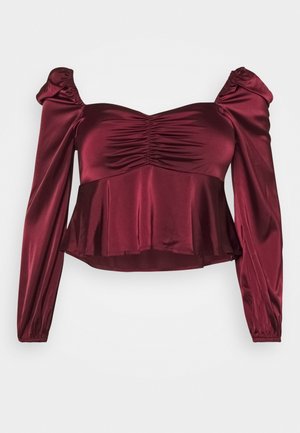 Bordowa satynowa bluzka z długim rękawem, marszczonym dekoltem typu off-shoulder i dołem typu peplum.