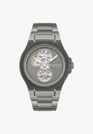 Stříbrné automatické hodinky z nerezové oceli s odhalenými převody, třemi ručičkami a značkou Kenneth Cole New York na kartáčovaném ciferníku.