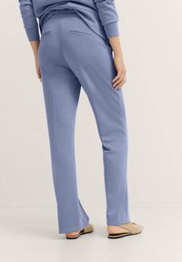 Light blue, long, straight-leg pants with back pockets and side slits at the hem. Smooth texture, made from a soft, stretchy fabric.
