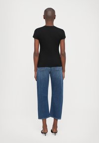 Black fitted T-shirt with short sleeves paired with high-waisted, wide-leg blue denim jeans. Smooth fabric and classic five-pocket design.
