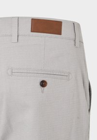 Grå byxor av texturerat tyg med en läderficka vid midjebandet och knappstängning på bakfickan.