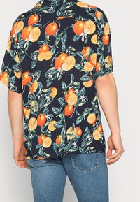 Camicia a maniche corte di colore blu scuro con un vivace motivo floreale arancione e limone, con foglie verdi e accenti floreali bianchi.