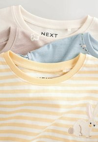 Three children's T-shirts: one yellow striped with a bunny design, one light blue, and one soft pink, all in cotton with crew necks.