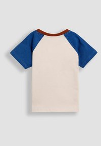 Baumwoll-T-Shirt mit Raglanärmeln. Körper in Creme, Ärmel in Blau und ein brauner Kragen. Weicher Stoff, lässiges Design und kurze Ärmel.