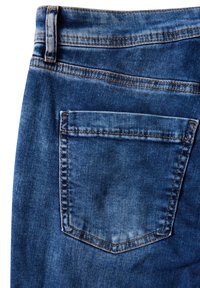 Tummansiniset farkut, joissa on näkyvät ompeleet ja yksi takatasku, joka on suorakulmainen ja jossa on hienovaraisia haalistumisvikoja.