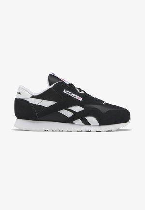 Zapatillas Reebok en blanco y negro que presentan material de ante y malla, puntera redondeada y suela de goma texturizada con acentos de logo.
